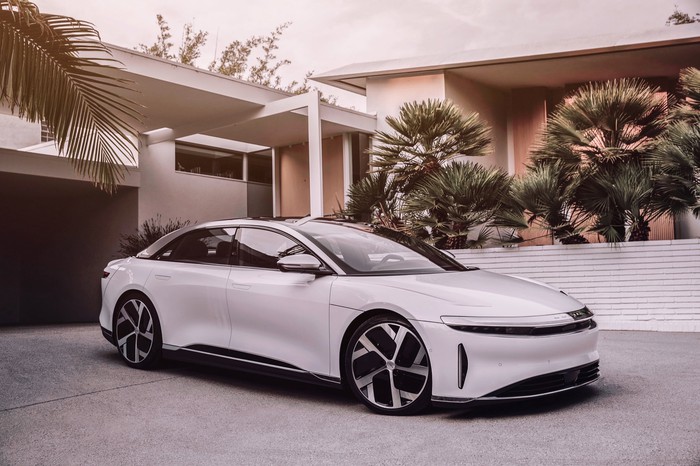 A white Lucid Air parked in front of a modern home.