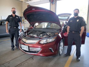 Tillsonburg firefighters Dennis Vandevyvere (left) and Chris Coldham stand next to an electric vehicle inside the Tillsonburg fire hall, one of a half dozen cars brought in by the Waterloo Region Electric Vehicle Association to help educate local firefighters on the new technology. (Chris Abbott/Norfolk and Tillsonburg News)