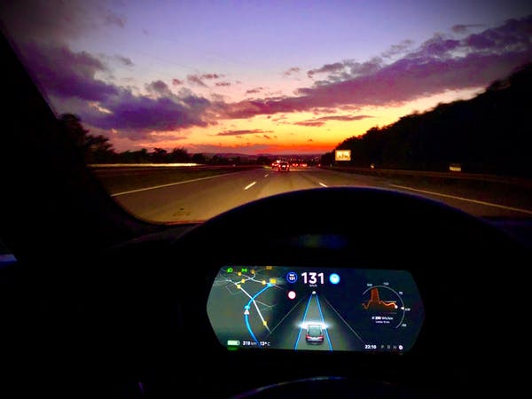 The dashboard seen from inside an electric car at sunset.