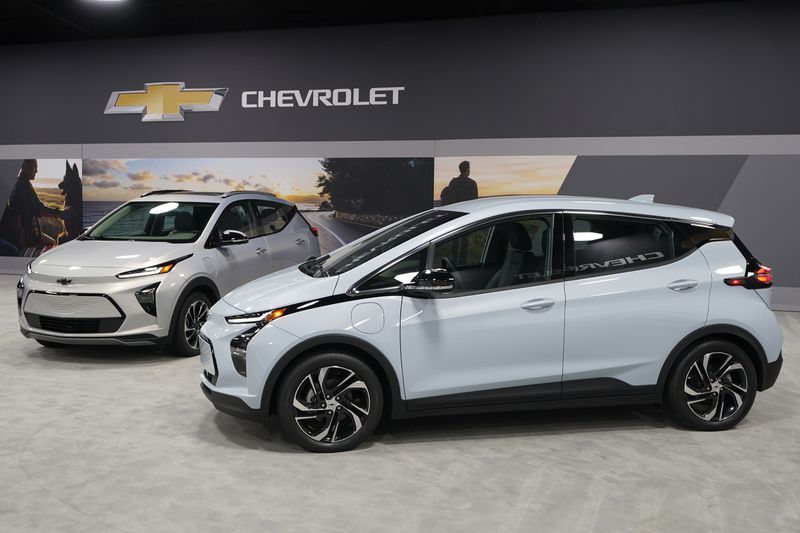 The 2022 Bolt EV, foreground, and EUV are displayed, Thursday, Feb. 11, in Milford, Mich. Whether people want them or not, automakers are rolling out multiple new electric vehicle models as the auto industry responds to stricter pollution regulations worldwide and calls to reduce emissions to fight climate change.  (AP Photo/Carlos Osorio)