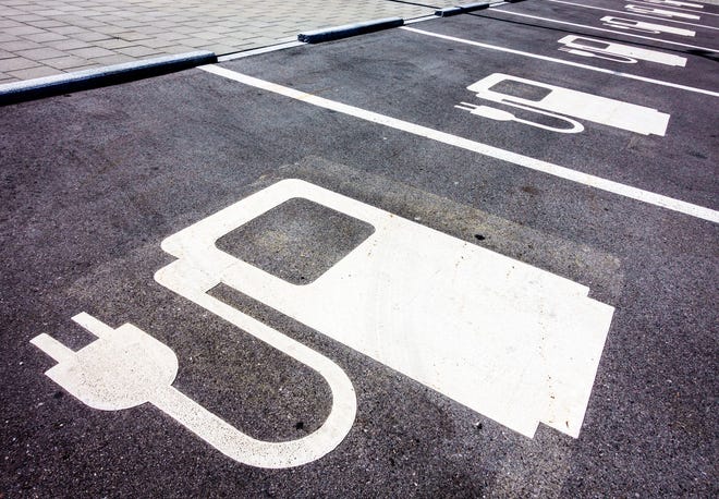 Electric vehicle charging symbols are painted on a row of parking spaces.