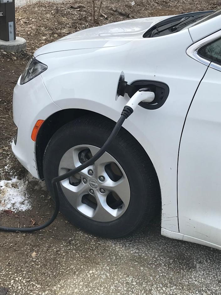 A Dodge Caravan hybrid, owned by the state Department of Conservation and Natural Resources, is hooked up to one of two new electric vehicle charging stations on March 4, 2021, at the Tom Ridge Environmental Center in Millcreek Township.