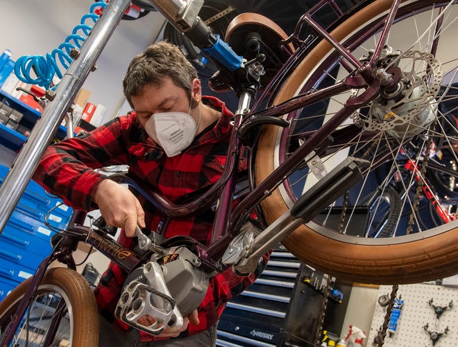 Bike mechanic Aaron Daigle works on an E-bike in the repair shop at Landry's Bicycles in Worcester.