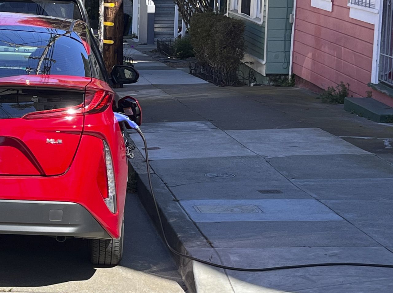 A charging cord for an electric vehicle is seen strung across a public sidewalk