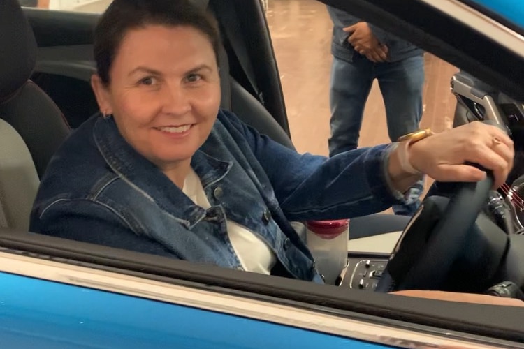 Woman sitting in new blue car in a show room smiling