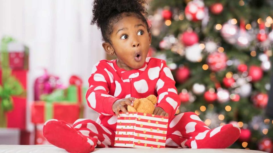 Surprised Black girl holding teddy bear toy on Christmas